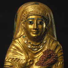<p><i>Mummy Cartonnage of a Woman</i>. Egypt, from Hawara. Roman Period, 1st century <small>C.E.</small> Linen, gilded gesso, glass, faience, 22<sup>11</sup>⁄<sub>16</sub> x 14<sup>5</sup>⁄<sub>8</sub> x 7<sup>1</sup>⁄<sub>2</sub> in. (57.6 × 37.2 × 19 cm). Brooklyn Museum, Charles Edwin Wilbour Fund, 69.35</p>