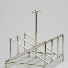 <p>Christopher Dresser (English, 1834–1904). <i>Toast Rack</i>, circa 1880. Silver, 5<sup>3</sup>⁄<sub>8</sub> x 5<sup>1</sup>⁄<sub>4</sub> x 4<sup>1</sup>⁄<sub>4</sub> in. (13.7 × 13.3 × 10.8 cm). Manufactured by Tiffany & Company (New York, active 1853–present). Brooklyn Museum, Gift of Marie Bernice Bitzer, by exchange, 1997.114</p>