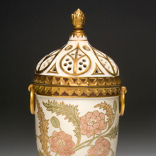 <p>Edward Lycett (American, b. England, 1833–1910). Faience Manufacturing Company (1881–92). <i>Covered Vase</i>, 1886–90. Cream-colored earthenware painted over ivory-glazed ground with polychrome enamels and flat and raised gold paste decoration. Nally-Stufano Collection</p>