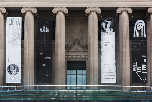 Straight on view of the front of the Museum showing only Kameelah Janan Rasheed's four banners from her exhibition Are We Reading Closely?, displayed among the building columns