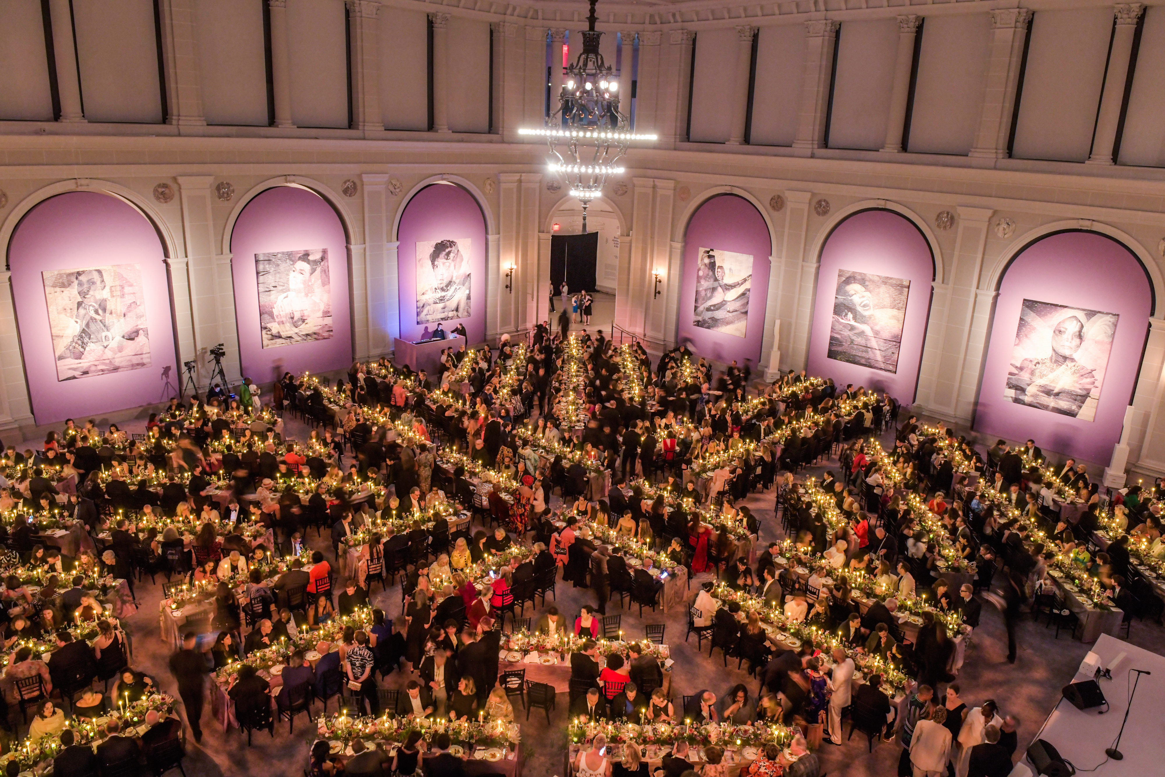 Party guests sitting at long candlelit tables 