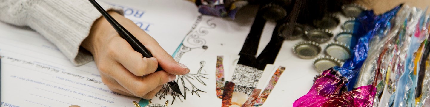 The hand of a student holding an ink pen and drawing in an art class