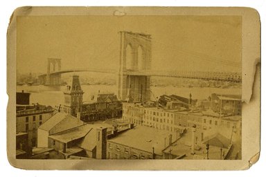 <em>"Brooklyn Bridge, view from land with buildings"</em>. Printed material. Brooklyn Museum. (F129_B79_C68_Pictures_of_Brooklyn_Brooklyn_Bridge_view_from_land_buildings.jpg