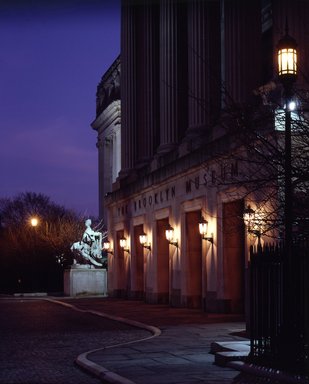 <em>"Brooklyn Museum: exterior. View of the Central section entrance at night from the entrance pathway, showing lit lamps and Manhattan statue in the background, 1990."</em>, 1990. Color transparency 4x5in, 4 x 5in (10.2 x 12.7 cm). Brooklyn Museum, Museum building. (Photo: Brooklyn Museum, S06_BEEi142.jpg