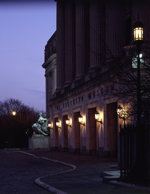 <em>"Brooklyn Museum: exterior. View of the Central section entrance at night from the entrance pathway, showing lit lamps and Manhattan statue in the background, 1990."</em>, 1990. Color transparency 4x5in, 4 x 5in (10.2 x 12.7 cm). Brooklyn Museum, Museum building. (Photo: Brooklyn Museum, S06_BEEi143.jpg