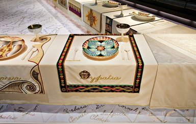 Judy Chicago (American, born 1939). <em>Hypatia Place Setting</em>, 1974-1979. Runner:Cotton/linen base fabric, woven interface support material (horsehair, wool, and linen), cotton twill tape, silk, synthetic gold cord, weft-faced bleached linen tapestry, single-ply wool weft, silk thread, wool thread, rubber rings
Plate: Porcelain with overglaze enamel (China paint) and paint,, Runner:51 1/2 x 29 7/8 in. (130.8 x 75.9 cm). Brooklyn Museum, Gift of The Elizabeth A. Sackler Foundation, 2002.10-PS-13. © artist or artist's estate (Photo: , 2002.10-PS-13_Hypatia_Jook_Leung_photo_9308r2.jpg)