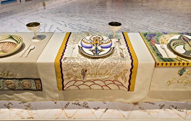 Judy Chicago (American, born 1939). <em>Trotula Place Setting</em>, 1974-1979. Runner:Off-white cotton in satin weave, muslin, woven interface support material (horsehair, wool, and linen), cotton twill tape, silk, synthetic gold cord, colored cotton floss, quilted and appliquéd fabrics, cotton thread
Plate: Porcelain with overglaze enamel (China paint), rainbow luster overglaze, and possibly paint, Runner: 51 3/8 x 29 3/8 in. (130.5 x 74.6 cm). Brooklyn Museum, Gift of The Elizabeth A. Sackler Foundation, 2002.10-PS-18. © artist or artist's estate (Photo: , 2002.10-PS-18_Trotula_Jook_Leung_photo_9328r2.jpg)