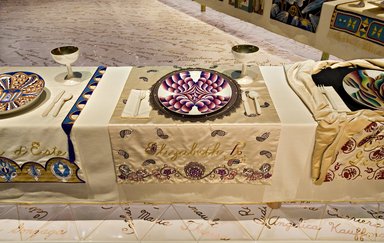 Judy Chicago (American, born 1939). <em>Elizabeth R. Place Setting</em>, 1974-1979. Runner: Silk satin, cotton/linen base fabric, woven interface support material (horsehair, wool, and linen), cotton twill tape, silk, synthetic gold cord, pearls, satin fabric, colored silk thread
Plate: Porcelain with overglaze enamel (China paint), rainbow luster glaze, silk chiffon covered plastic ring, linen, dyed lace, gold wrapped cord, thread, and pearls, Runner:52 1/2 x 30 1/4 in. (133.4 x 76.8 cm). Brooklyn Museum, Gift of The Elizabeth A. Sackler Foundation, 2002.10-PS-24. © artist or artist's estate (Photo: , 2002.10-PS-24_Elizabeth_R_Jook_Leung_photo_9340r2.jpg)