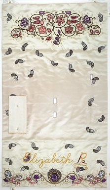 Judy Chicago (American, born 1939). <em>Elizabeth R. Place Setting</em>, 1974-1979. Runner: Silk satin, cotton/linen base fabric, woven interface support material (horsehair, wool, and linen), cotton twill tape, silk, synthetic gold cord, pearls, satin fabric, colored silk thread
Plate: Porcelain with overglaze enamel (China paint), rainbow luster glaze, silk chiffon covered plastic ring, linen, dyed lace, gold wrapped cord, thread, and pearls, Runner:52 1/2 x 30 1/4 in. (133.4 x 76.8 cm). Brooklyn Museum, Gift of The Elizabeth A. Sackler Foundation, 2002.10-PS-24. © artist or artist's estate (Photo: , 2002.10-PS-24_runner_PS1.jpg)
