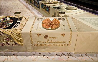 Judy Chicago (American, born 1939). <em>Anna van Schurman Place Setting</em>, 1974-1979. Runner:Cotton/linen base fabric, woven interface support material (horsehair, wool, and linen), cotton twill tape, silk, synthetic gold cord, thread, perle cotton, cotton floss
Plate: Porcelain with overglaze enamel (China paint), metallic yellow luster glaze, and iridescent luster glaze, Runner: 52 1/8 x 30 in. (132.4 x 76.2 cm). Brooklyn Museum, Gift of The Elizabeth A. Sackler Foundation, 2002.10-PS-26. © artist or artist's estate (Photo: , 2002.10-PS-26_Anna_van_Schurman_Jook_Leung_photo_9344r2.jpg)