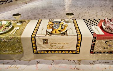Judy Chicago (American, born 1939). <em>Sojourner Truth Place Setting</em>, 1974-1979. Runner: Cotton/linen base fabric, muslin, flannel, cotton twill tape, silk, synthetic gold cord, cotton triangles, tapestry woven bands, cotton bias tape, cotton floss, thread
Plate: Porcelain with overglaze enamel (China paint), rainbow luster glaze, and paint, Runner: 51 5/8 x 30 1/8 in. (131.1 x 76.5 cm). Brooklyn Museum, Gift of The Elizabeth A. Sackler Foundation, 2002.10-PS-31. © artist or artist's estate (Photo: , 2002.10-PS-31_Sojourner_Truth_Jook_Leung_photo_9363r2.jpg)