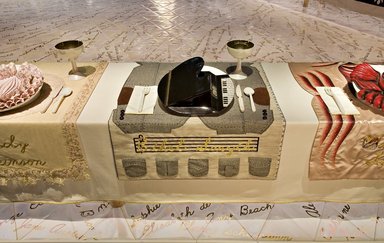 Judy Chicago (American, born 1939). <em>Ethel Smyth Place Setting</em>, 1974-1979. Runner: Cotton/linen base fabric, woven interface support material (horsehair, wool, and linen), cotton twill tape, silk, synthetic gold cord, wool, glazed cotton carpet thread, leather covered buttons, metal shanks, suede leather, tape measure, soutache, thread
Plate: Porcelain with overglaze enamel (China paint), enamel paint, and gold glaze, Runner: 52 x 30 1/8 in. (132.1 x 76.5 cm). Brooklyn Museum, Gift of The Elizabeth A. Sackler Foundation, 2002.10-PS-35. © artist or artist's estate (Photo: , 2002.10-PS-35_Ethyl_Smith_Jook_Leung_photo_9371r2.jpg)