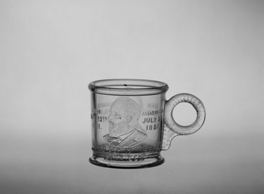  <em>Mug (Abraham Lincoln & James Garfield)</em>, ca. 1881. Glass, 2 5/8 x 3 7/8 x 2 5/8 in. (6.7 x 9.8 x 6.7 cm). Brooklyn Museum, Gift of Mrs. William Greig Walker by subscription, 40.182. Creative Commons-BY (Photo: Brooklyn Museum, 40.182_bw.jpg)