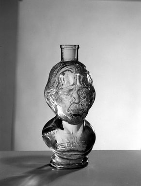 American. <em>Bottle, Bust of Henry Ward Beecher</em>, 1887. Glass, 6 3/4 x 3 x 3 in. (17.1 x 7.6 x 7.6 cm). Brooklyn Museum, Gift of Mrs. William Greig Walker by subscription, 40.279. Creative Commons-BY (Photo: Brooklyn Museum, 40.279_acetate_bw.jpg)