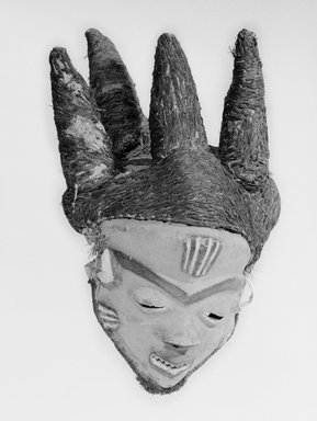 Pende (Western). <em>Mask (Mbuya) of Chief (Phumbu)</em>, late 19th–early 20th century. Wood, pigment, raffia, fiber, 17 5/16 x 11 in.  (44.0 x 27.9 cm). Brooklyn Museum, Gift of Arturo and Paul Peralta-Ramos, 56.6.4. Creative Commons-BY (Photo: Brooklyn Museum, 56.6.4_bw_SL1.jpg)