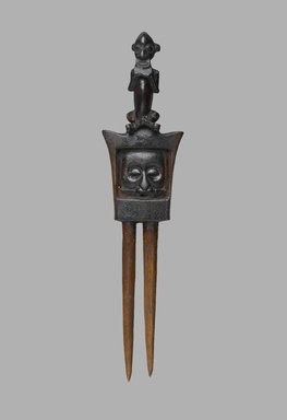 Yaka. <em>Comb with Face, Lizard and Cross-legged Figure (Yisanuna)</em>, late 19th or early 20th century. Wood, 5 3/4 x 1 1/2 x 1/2 in. (14.6 x 3.8 x 1.3 cm). Brooklyn Museum, Bequest of Laura L. Barnes, 67.25.34. Creative Commons-BY (Photo: Brooklyn Museum, 67.25.34_front_PS2.jpg)