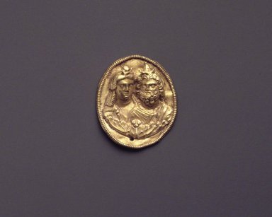  <em>Medallion with Busts of Isis and Serapis</em>, after 300 B.C.E. Gold, 1 1/8 x 15/16 x 1/4 in. (2.8 x 2.4 x 0.6 cm). Brooklyn Museum, Charles Edwin Wilbour Fund, 73.85. Creative Commons-BY (Photo: Brooklyn Museum, 73.85_transpc002.jpg)