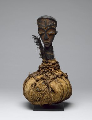 Tsogho. <em>Reliquary Guardian Figure (Boumba Bwiti)</em>, late 19th or early 20th century. Wood, raffia, metal, bark cloth, glass, feathers, 12 x 7 1/2 in. (30.5 x 18.4 cm). Brooklyn Museum, Gift of Mr. and Mrs. John A. Friede, 74.121.7. Creative Commons-BY (Photo: Brooklyn Museum, 74.121.7_front_PS6.jpg)