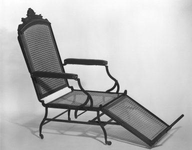 Cavedra B. Sheldon. <em>Folding Invalid Chair</em>, Patented 1876; Made ca. 1876–1895. Iron, walnut, and new caning and upholstery, Open: 46 3/4 x 27 x 77 1/4 in. (118.7 x 68.6 x 196.2 cm). Brooklyn Museum, H. Randolph Lever Fund, 81.34. Creative Commons-BY (Photo: Brooklyn Museum, 81.34_overall_bw_IMLS.jpg)
