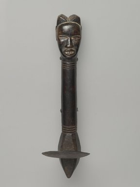 Feia Tomekpa (Dan, flourished 1940s–early 1950s). <em>Ceremonial Hoe</em>, 20th century. Wood, iron, 14 1/8 x 2 1/4 x 4 1/16 in. (35.9 x 5.7 x 10.3 cm). Brooklyn Museum, Gift of Mr. and Mrs. Brian S. Leyden, 87.216.1. Creative Commons-BY (Photo: Brooklyn Museum, 87.216.1_front_PS6.jpg)