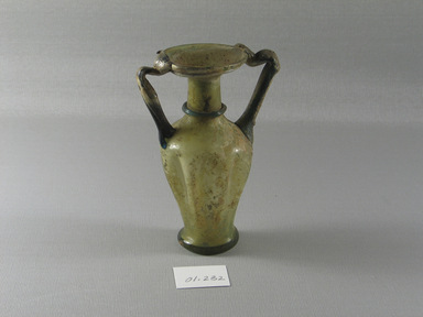 Roman. <em>Flask with Folded Body Decoration</em>, 3rd-5th century C.E. Glass, 4 15/16 x 3 3/8 x 2 1/4 in. (12.5 x 8.5 x 5.7 cm). Brooklyn Museum, Gift of Robert B. Woodward, 01.232. Creative Commons-BY (Photo: Brooklyn Museum, CUR.01.232_view1.jpg)