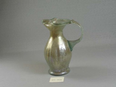 Roman. <em>Jug of Molded Green Glass</em>, 1st-5th century C.E. Glass, 5 3/16 x 2 15/16 x 4 1/16 in. (13.1 x 7.4 x 10.3 cm). Brooklyn Museum, Gift of Robert B. Woodward, 01.313. Creative Commons-BY (Photo: Brooklyn Museum, CUR.01.313_view1.jpg)