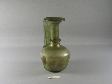 Roman. <em>Bottle with Folded Body Decoration</em>, 4th-5th century C.E. Glass, 6 9/16 x Diam. 3 7/8 in. (16.6 x 9.8 cm). Brooklyn Museum, Gift of Robert B. Woodward, 01.384. Creative Commons-BY (Photo: Brooklyn Museum, CUR.01.384_view1.jpg)