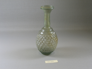 Roman. <em>Bottle with Stylized Grape Pattern</em>, 3rd century C.E. Glass, 2 5/8 x 5 11/16 in. (6.6 x 14.4 cm). Brooklyn Museum, Gift of Robert B. Woodward, 01.57. Creative Commons-BY (Photo: Brooklyn Museum, CUR.01.57_view1.jpg)