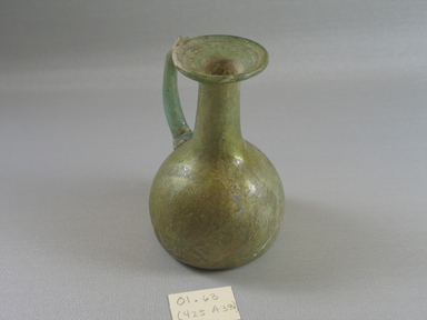 Roman. <em>Jug of Blown Green Glass</em>, 1st-5th century C.E. Glass, 4 5/8 x greatest diam. 2 7/8 in. (11.7 x 7.3 cm). Brooklyn Museum, Gift of Robert B. Woodward, 01.63. Creative Commons-BY (Photo: Brooklyn Museum, CUR.01.63_view1.jpg)