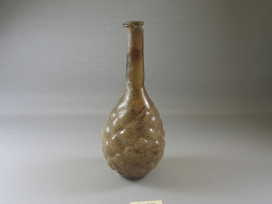 Roman. <em>Bottle with Stylized Grape Pattern</em>, 3rd century C.E. Glass, Greatest diam. 3 5/16 x 7 7/16 in. (8.4 x 18.9 cm). Brooklyn Museum, Gift of Robert B. Woodward, 01.88. Creative Commons-BY (Photo: Brooklyn Museum, CUR.01.88_view1.jpg)