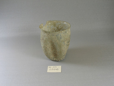Roman. <em>Tumbler with Folded Body Decoration</em>, mid-1st to early 3rd century C.E. Glass, 3 3/8 x greatest diam. 2 15/16 in. (8.5 x 7.5 cm) . Brooklyn Museum, Gift of Robert B. Woodward, 09.54. Creative Commons-BY (Photo: Brooklyn Museum, CUR.09.54_view1.jpg)