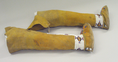 Osage. <em>Girl's Moccasins Attached to Leggings</em>, late 19th–early 20th century. Hide, pigment, beads, 20 1/2 x 7 7/8 in.  (52.0 x 20.0 cm). Brooklyn Museum, Museum Expedition 1911, Museum Collection Fund, 11.694.9002a-b. Creative Commons-BY (Photo: Brooklyn Museum, CUR.11.694.9002a-b_view02.jpg)