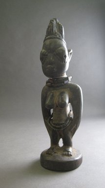 Yorùbá artist. <em>Female twin figure (Ère Ìbejì) with tunic</em>, 20th century. Wood, cloth, leather, coconut shell, glass and shell beads, cowrie shells, figure w/o cloak: 10 1/4 x 3 x 2 3/4 in. Brooklyn Museum, Gift of Mr. and Mrs. Lee Lorenz, 1993.179.4a-b. Creative Commons-BY (Photo: Brooklyn Museum, CUR.1993.179.4a_overall.jpg)