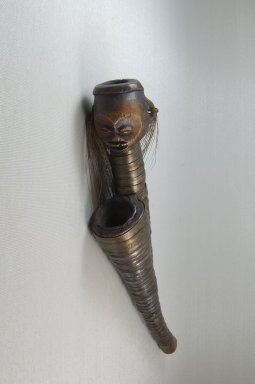 Ngbaka. <em>Pipe with Human Face (Boka)</em>, late 19th or early 20th century. Wood, copper alloy, iron, cowrie shell, 21 x 2 3/4 x 4in. (53.3 x 7 x 10.2cm). Brooklyn Museum, Museum Expedition 1922, Robert B. Woodward Memorial Fund, 22.1254. Creative Commons-BY (Photo: Brooklyn Museum, CUR.22.1254_front_PS5.jpg)