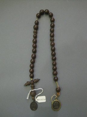 <em>String of Brown Beads with Medallion</em>. synthetic, metal, 19 in. (48.3 cm). Brooklyn Museum, Gift of Judge Townsend Scudder, 24.437.60. Creative Commons-BY (Photo: Brooklyn Museum, CUR.24.437.60.jpg)