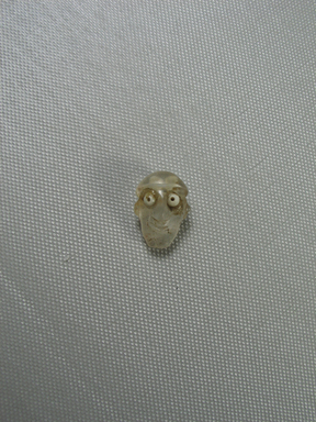  <em>Small Bead in Form of a Human Head</em>. Rock crystal?, glass, 7/8 × 5/8 × 1/2 in. (2.3 × 1.6 × 1.3 cm). Brooklyn Museum, Charles Edwin Wilbour Fund, 37.1113E. Creative Commons-BY (Photo: Brooklyn Museum, CUR.37.1113E_view01.jpg)