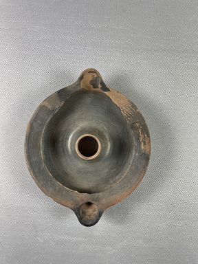 Greek. <em>Small Circular Lamp</em>, 305 B.C.E.-395 C.E. Clay, 4 3/16 × 5/8 × 5 1/16 in. (10.6 × 1.6 × 12.9 cm). Brooklyn Museum, Charles Edwin Wilbour Fund, 37.1591E. Creative Commons-BY (Photo: Brooklyn Museum, CUR.37.1591E_view01.jpeg)
