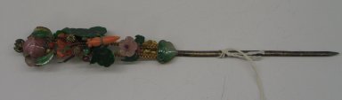  <em>Hair Pin</em>, early 20th century. Gilt, jade, coral, garnet, pink tourmaline, feather, 11 7/16 x 1 in. (29.1 x 2.5 cm). Brooklyn Museum, Frank L. Babbott Fund, 37.371.250. Creative Commons-BY (Photo: Brooklyn Museum, CUR.37.371.250_front.jpg)