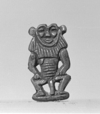  <em>Bes-Image Amulet</em>, 1539–1075 B.C.E. Faience, 1 1/4 × 11/16 × 3/16 in. (3.1 × 1.7 × 0.5 cm). Brooklyn Museum, Charles Edwin Wilbour Fund, 37.915E. Creative Commons-BY (Photo: Brooklyn Museum, CUR.37.915E_negL_897_12A_bw.jpg)