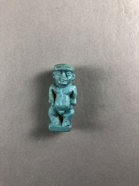  <em>Amulet of Pataikos</em>, 664-332 B.C.E. Faience, 1 7/16 × 5/8 × 1/2 in. (3.6 × 1.6 × 1.2 cm). Brooklyn Museum, Charles Edwin Wilbour Fund, 37.989E. Creative Commons-BY (Photo: , CUR.37.989E_view01.jpg)
