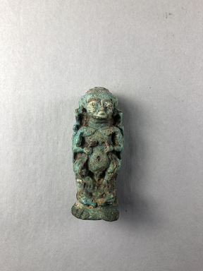  <em>Amulet of Pataikos Flanked by Goddesses</em>, 664-30 B.C.E. Faience, 2 1/2 × 1 1/16 × 1 in. (6.4 × 2.7 × 2.5 cm). Brooklyn Museum, Charles Edwin Wilbour Fund, 37.996E. Creative Commons-BY (Photo: , CUR.37.996E_view01.jpg)