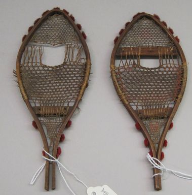 Abenaki. <em>Pair of Model Snowshoes with red tassels</em>. Hide, wool, 7 5/16 x 2 7/8 in.  (18.5 x 7.3 cm). Brooklyn Museum, Gift of Percy C. Madeira, Jr., 42.244.5a-b. Creative Commons-BY (Photo: , CUR.42.244.5a-b.jpg)