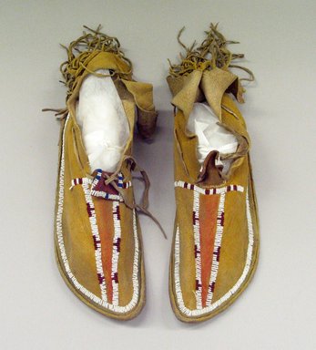 Kiowa. <em>Pair of Beaded Moccasins with Hard-soles</em>, 1900-1915. Hide, beads, A:  2 3/4 x 3 1/2 x 11 in. (7 x 8.9 x 27.9 cm) [not including fringe]. Brooklyn Museum, Gift of Marie and Clarence Spader in memory of Clinton Spader and his wife, Marie Louise Spader, 49.219a-b. Creative Commons-BY (Photo: Brooklyn Museum, CUR.49.219a-b.jpg)