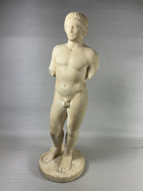 Classical; Alexandrian?. <em>Nude Young Man Standing on Circular Base</em>, 2nd century B.C.E. and later, or 19th century C.E. Marble, 13 3/4 × 5 5/16 × 4 5/16 in. (35 × 13.5 × 11 cm). Brooklyn Museum, Gift of Albert Gallatin, 50.61. Creative Commons-BY (Photo: Brooklyn Museum, CUR.50.61_view01.jpg)