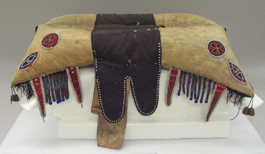 Red River Metis. <em>Pad Saddle</em>, early 19th century. Hide, beads, Stroud cloth, quills, cotton fringe, silk ribbon, deer hair, glass beads, brass, 26 x 18 1/2 in. (66 x 47 cm). Brooklyn Museum, Henry L. Batterman Fund and the Frank Sherman Benson Fund, 50.67.14. Creative Commons-BY (Photo: Brooklyn Museum, CUR.50.67.14_view1.jpg)