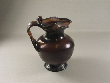 Roman. <em>Pitcher with Trefoil Mouth and Handles</em>, 4th century C.E. Glass, 6 9/16 x greatest diam. 5 7/16 in. (16.7 x 13.8 cm). Brooklyn Museum, Charles Edwin Wilbour Fund, 59.35.1. Creative Commons-BY (Photo: Brooklyn Museum, CUR.59.35.1_view1.jpg)