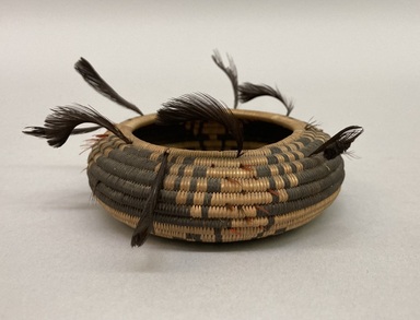 Pomo. <em>Miniature Coiled Basket with feathers along the edge</em>. Bulrush, sedge root, quail feather, redheaded woodpecker feather, 1 3/16 x 1 15/16in. (3 x 5cm). Brooklyn Museum, Gift of Mr. and Mrs. Francis T. Christy, 69.55.3. Creative Commons-BY (Photo: Brooklyn Museum, CUR.69.55.3.jpg)