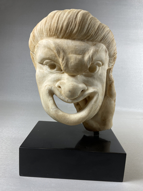 Roman. <em>Comic Mask, Held by a Right Hand</em>, perhaps 2nd century C.E. Marble, 7 1/2 × 5 1/4 × 3 9/16 in. (19 × 13.3 × 9 cm). Brooklyn Museum, Gift of Julius J. Ivanitsky in memory of his parents, Jacob and Ida Ivanitsky, 79.119.2. Creative Commons-BY (Photo: Brooklyn Museum, CUR.79.119.2_view01.jpg)