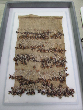  <em>Ceremonial Garment</em>. Barkcloth, shell, seeds, fiber, sennit, feathers, 27 x 15 3/8 in. (68.6 x 39.1 cm). Brooklyn Museum, Gift of Marcia and John Friede and Mrs. Melville W. Hall, 87.218.96. Creative Commons-BY (Photo: , CUR.87.218.96_overall.jpg)