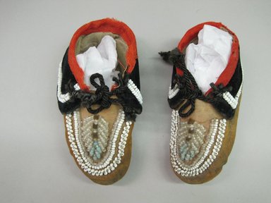 Haudenosaunee. <em>Infant's Moccasins</em>, ca. 1890-1920. Hide, velvet, cloth, beads, cord, 1 7/8 × 2 1/4 × 5 1/4 in. (4.8 × 5.7 × 13.3 cm). Brooklyn Museum, Gift of the Edward J. Guarino Collection in honor of Charlotte Picariello, 2016.11.25a-b. Creative Commons-BY (Photo: Brooklyn Museum, CUR.TL2016.18.25_top.jpg)